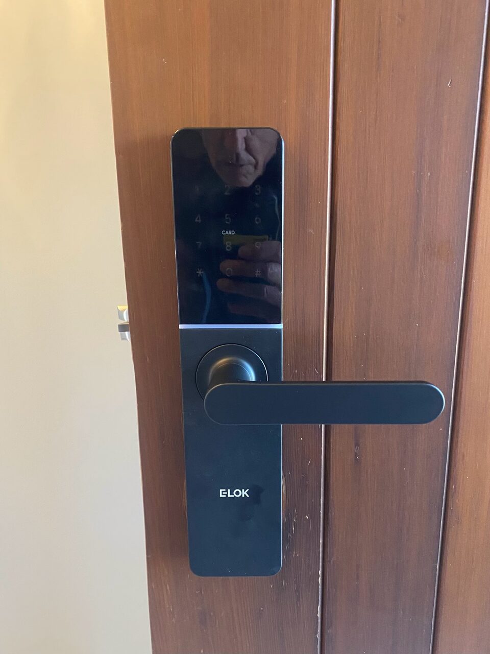 Black smart lock with horizontal lever handle installed on a timber door by Bay Locksmiths